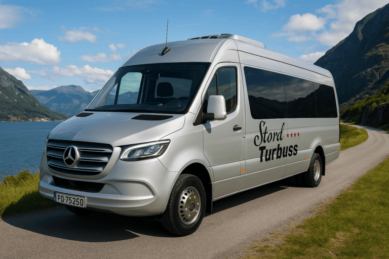 Moderne Mercedes-buss fra Stord Turbuss som kjører langs en fjord med fjell i bakgrunnen, perfekt for gruppereiser og transport i regionen.